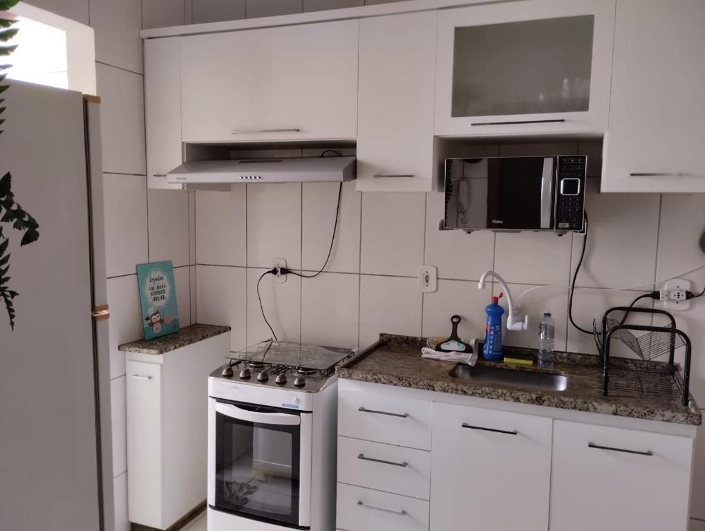 uma cozinha com armários brancos e um forno com placa de fogão em Andres' Home Vila Bretas em Governador Valadares