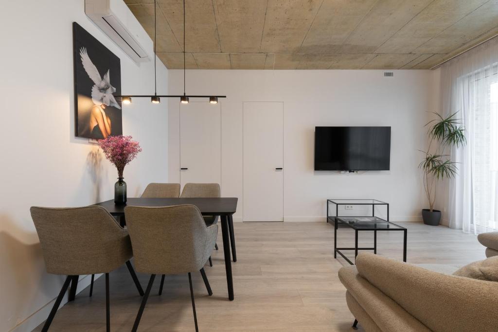 una sala da pranzo con tavolo, sedie e TV di Bossa Nova - modern 2 bedroom apartment in the center a Vilnius