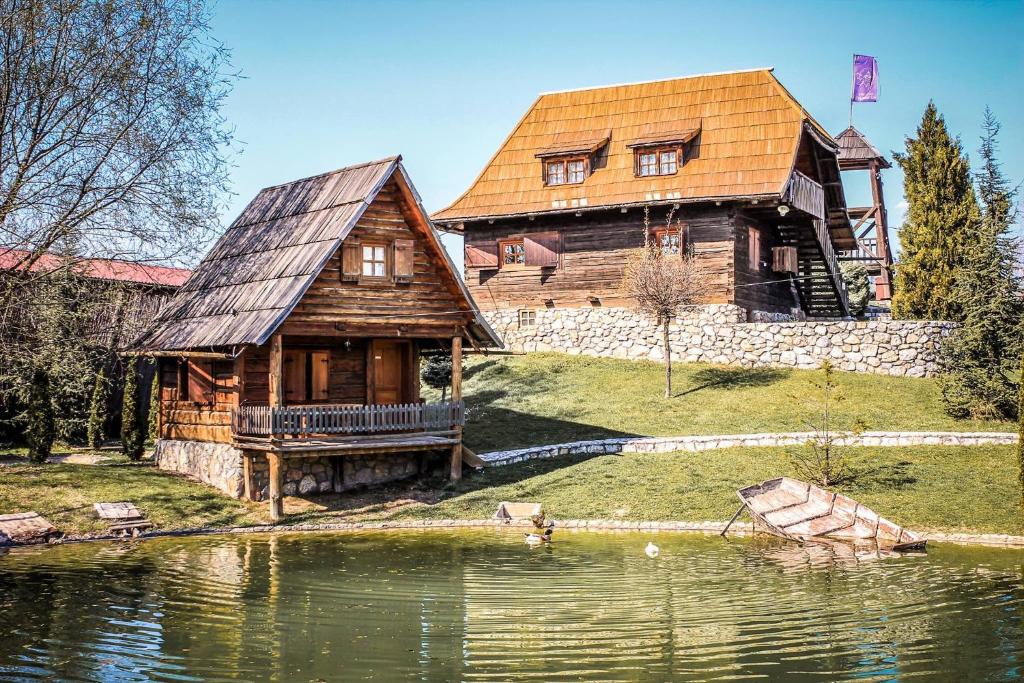 a large wooden house sitting next to a lake at Etno selo Stanišići Etno kuće in Dijelovi