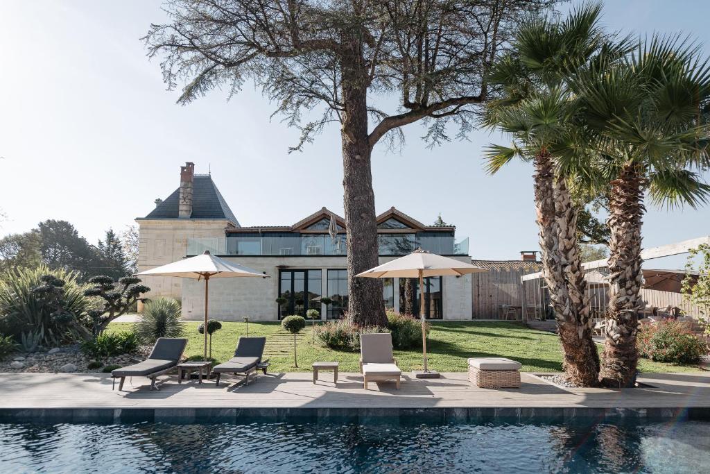 - une piscine avec des chaises et des parasols à côté d'une maison dans l'établissement Château Grand-Arnaud, à Vignac