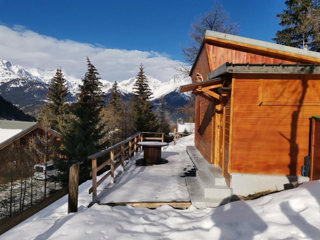 una cabaña en la nieve con montañas en el fondo en Petit chalet Valfréjus pied des pistes en Modane