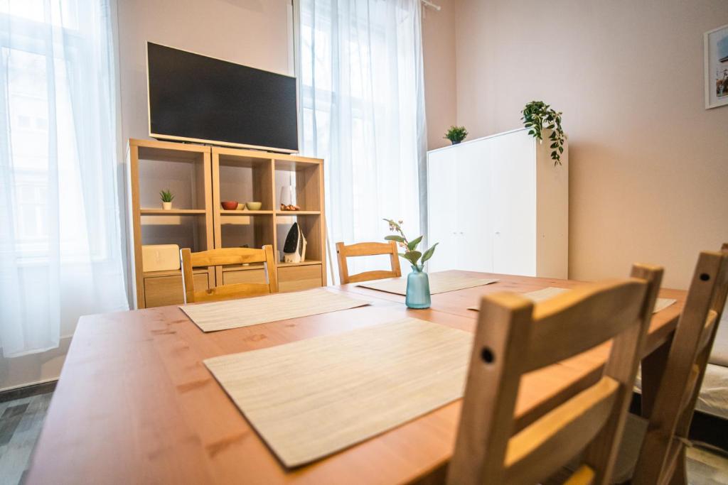 a dining room with a wooden table and a flat screen tv at Entire Flat in Kecskemét Center in Kecskemét