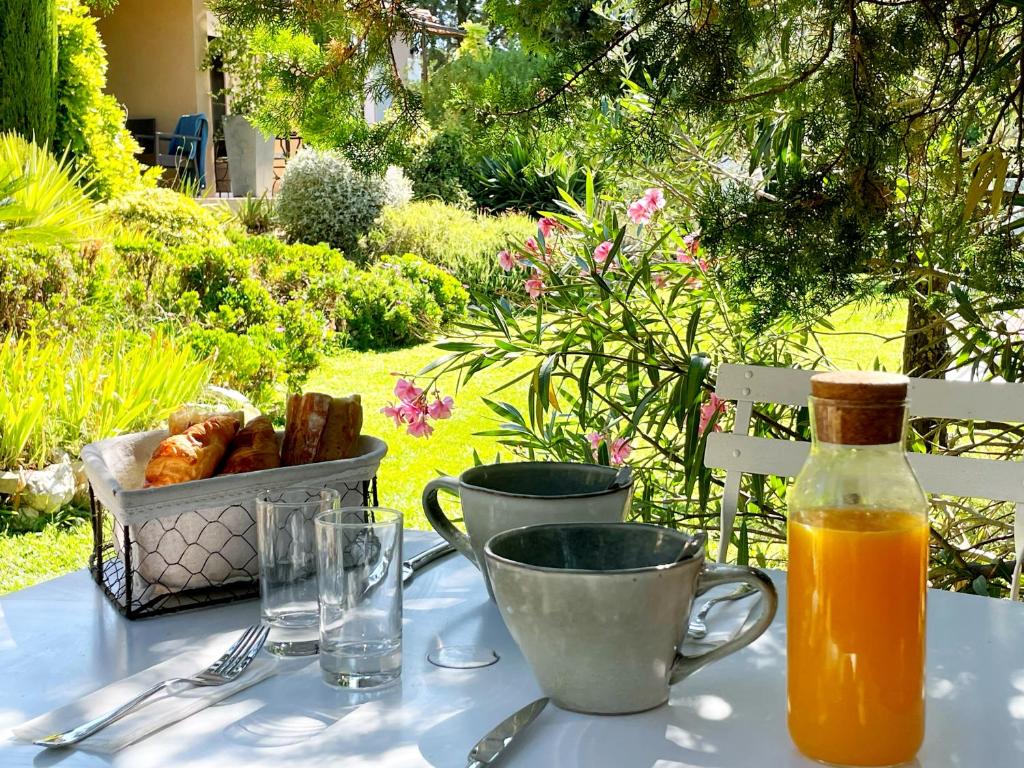 einen Tisch mit einer Flasche Orangensaft und einem Korb Brot in der Unterkunft Mas des Marguerites in Maussane-les-Alpilles