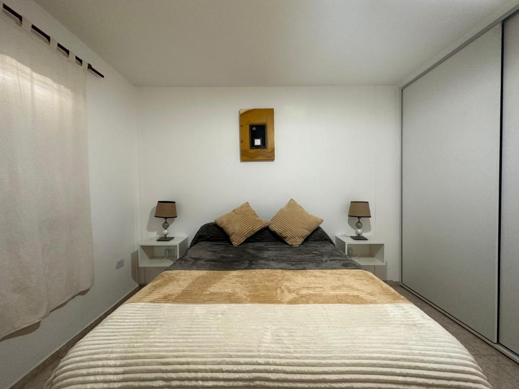1 dormitorio con 1 cama grande y 2 mesitas de noche en Pueblo Dorado Departamentos en Malargüe