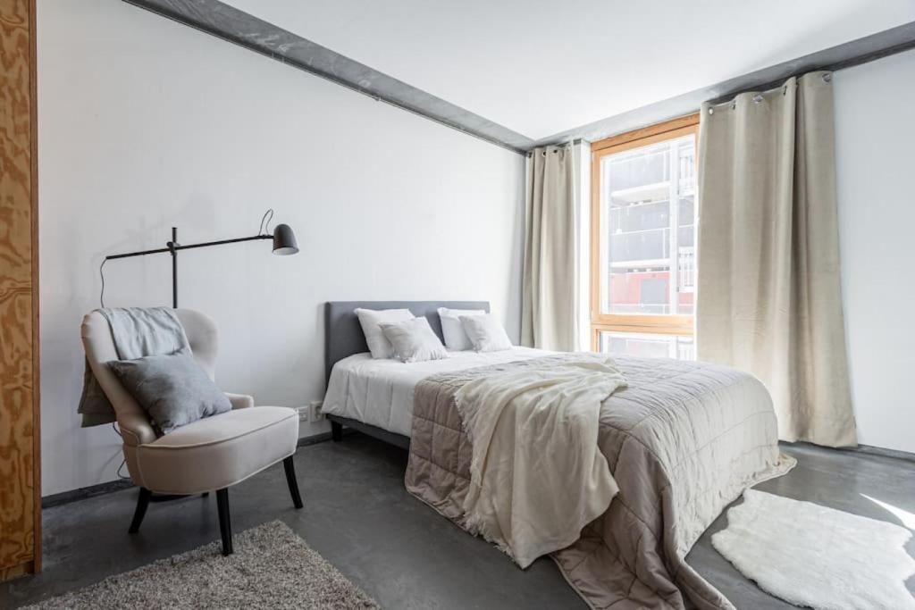 a bedroom with a bed and a chair and a window at Convinient Studio 25 min to city in Stockholm