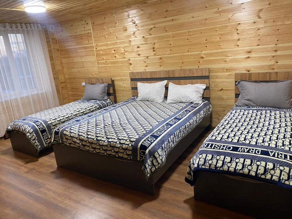 two beds in a room with wooden walls at Syi-Ordo Hotel in Pokrovka