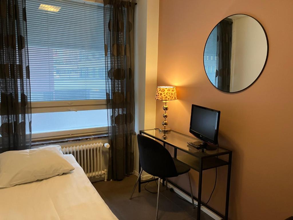 1 dormitorio con escritorio, cama y espejo en Hotel Harriet en Turku