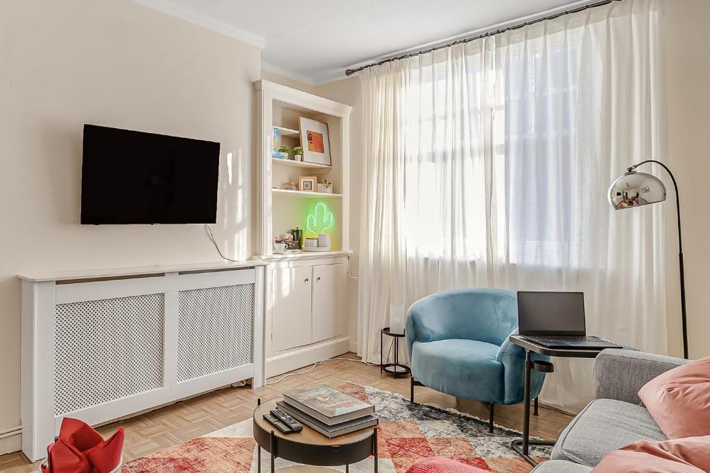 a living room with a blue chair and a television at The Covent Courtyard Flat in London