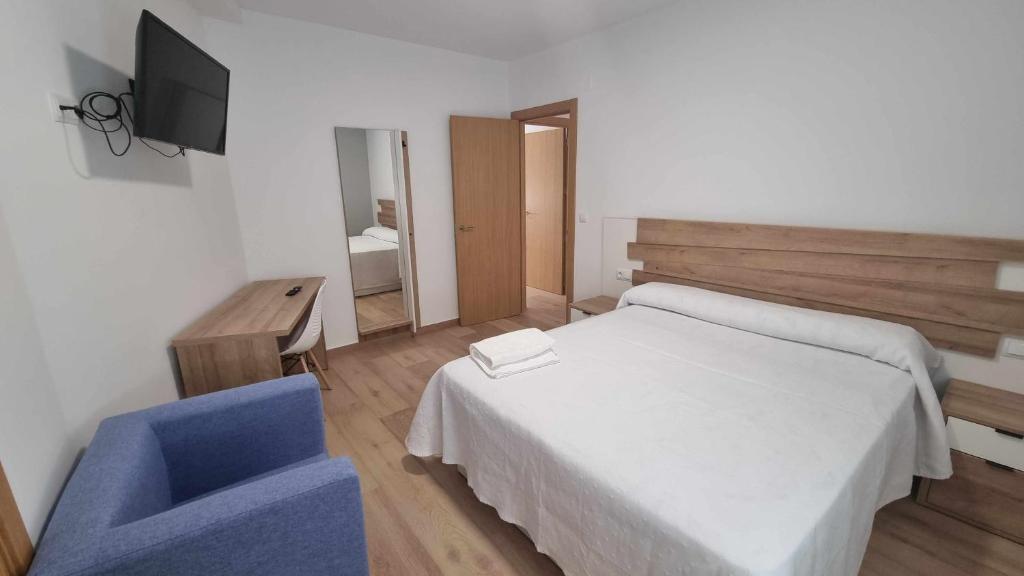 1 dormitorio con 1 cama blanca y 1 silla azul en ALQUILAZ Garaje incluido Cerca casco histórico, en Zamora