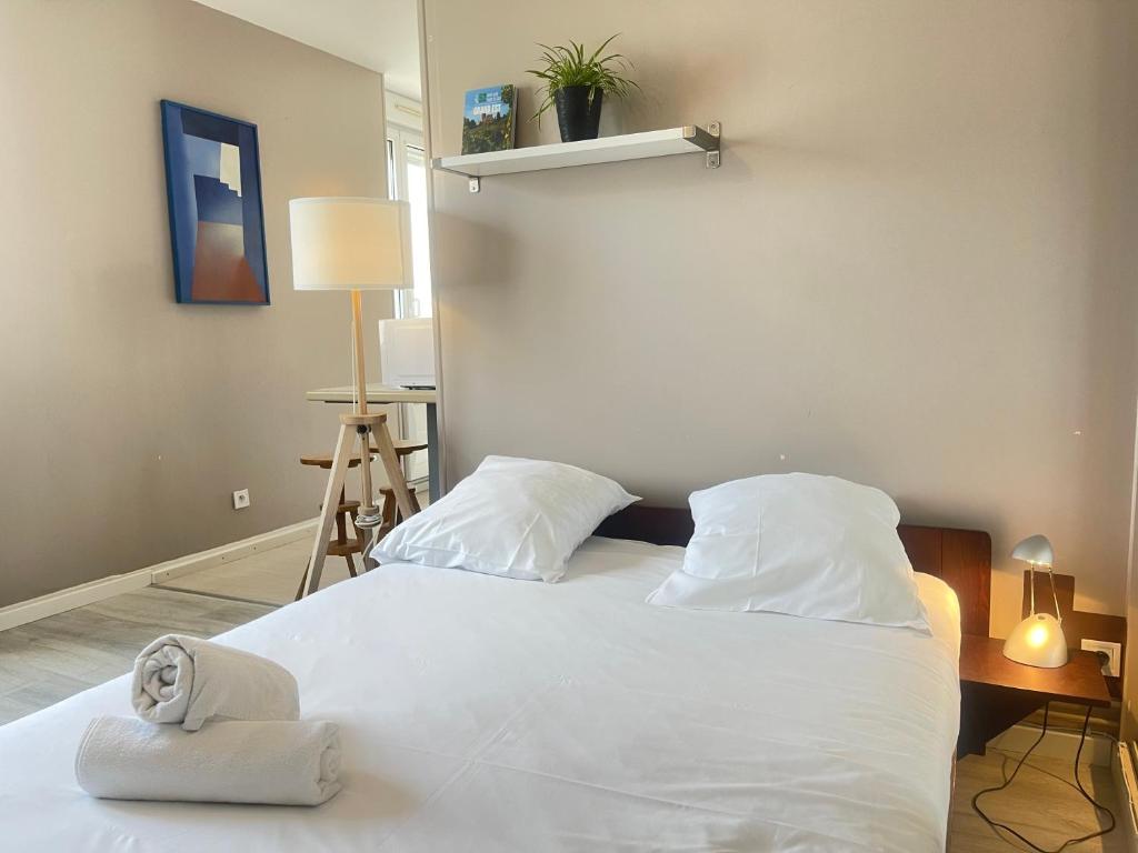 um quarto com uma cama branca e toalhas em Au Coin de YourHostHelper em Reims