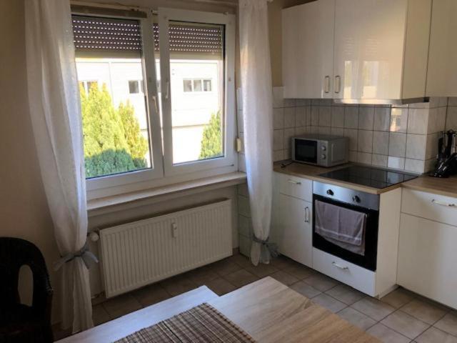 een keuken met witte kasten, een magnetron en een raam bij Sol Ferienwohnung in Rodenbach