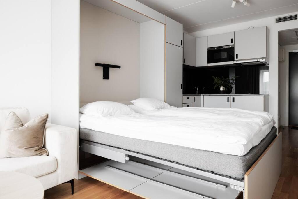 a white bedroom with a bed and a chair at Sleek Urban Studio w. work place in Kottla