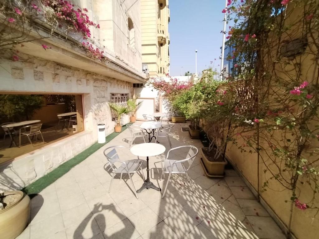 um pátio com uma mesa, cadeiras e plantas em فندق روتانة الفرسان بالحمرا em Jeddah