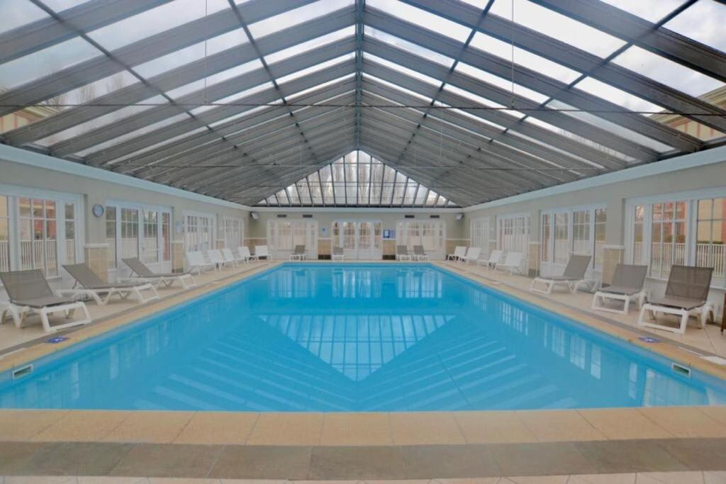 una gran piscina con sillas y techo en 6-person apartment with swimming pool tennis court and free parking REF25, en Le Touquet-Paris-Plage