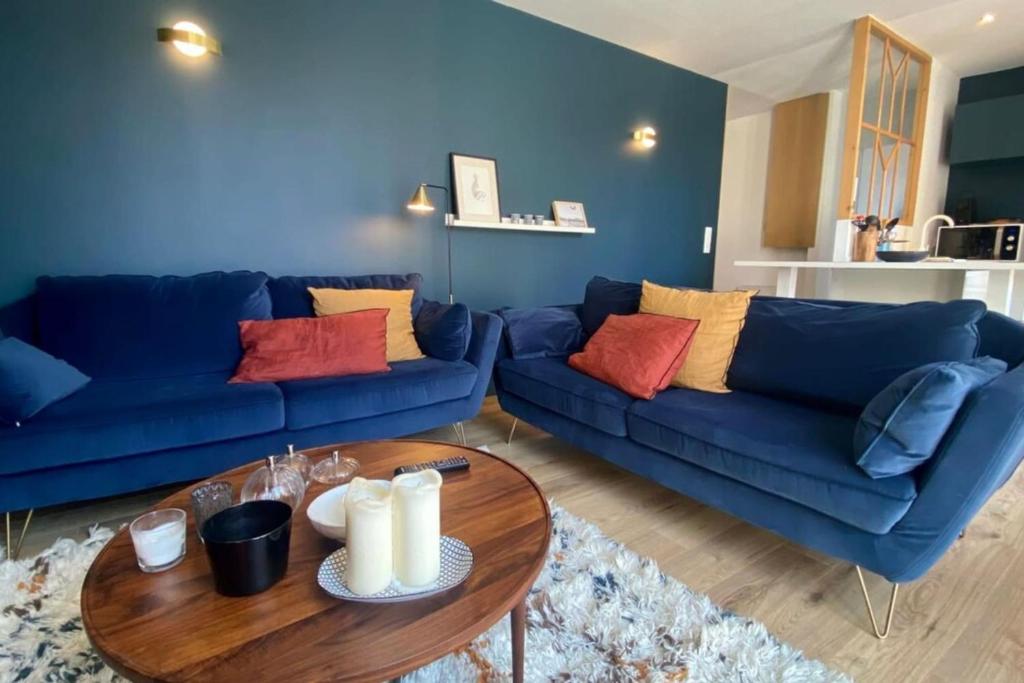 a living room with two blue couches and a table at Cosy flat close to the sea with large terrace in Le Touquet-Paris-Plage