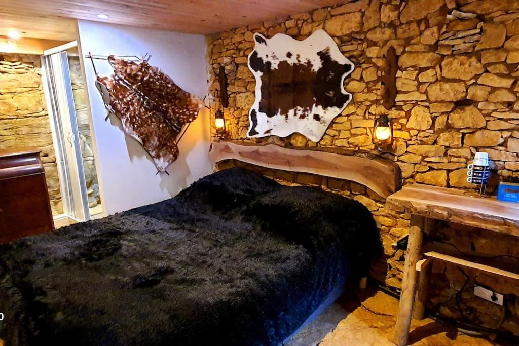 Un dormitorio con una pared de piedra y una cama. en Chambre rupestre indépendante dans gite du XVIII, en Carsac-Aillac
