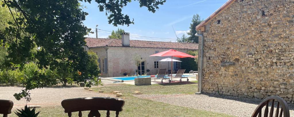 a stone house with a pool and a red umbrella at Le Reve de Breuillac in Surin