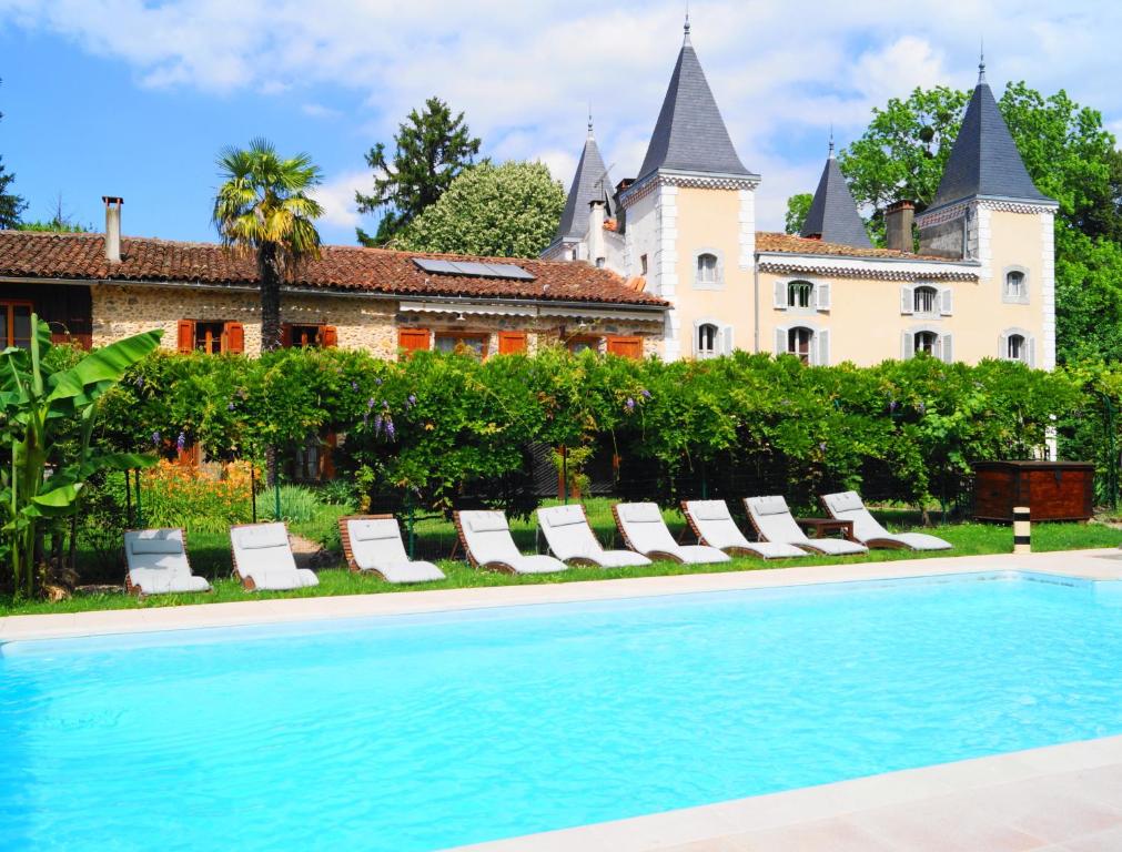 a swimming pool in front of a house with a castle at Hotel Logis - Chateau de Beauregard in Saint-Girons