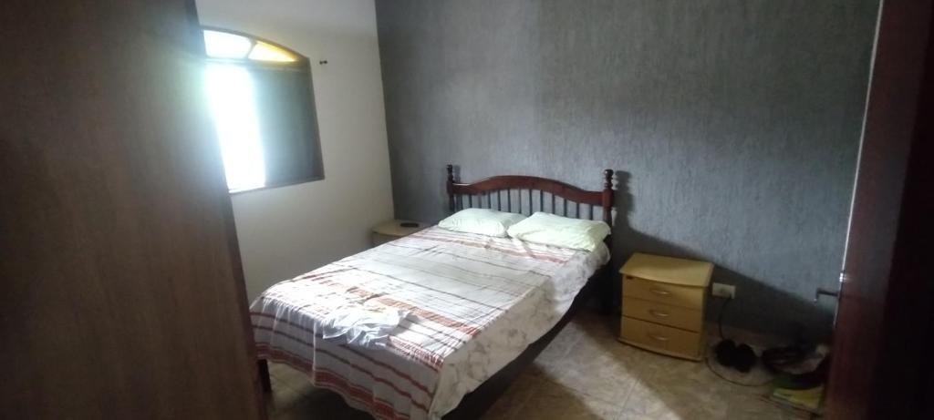um pequeno quarto com uma cama e um candeeiro em Casa Litoral em Peruíbe