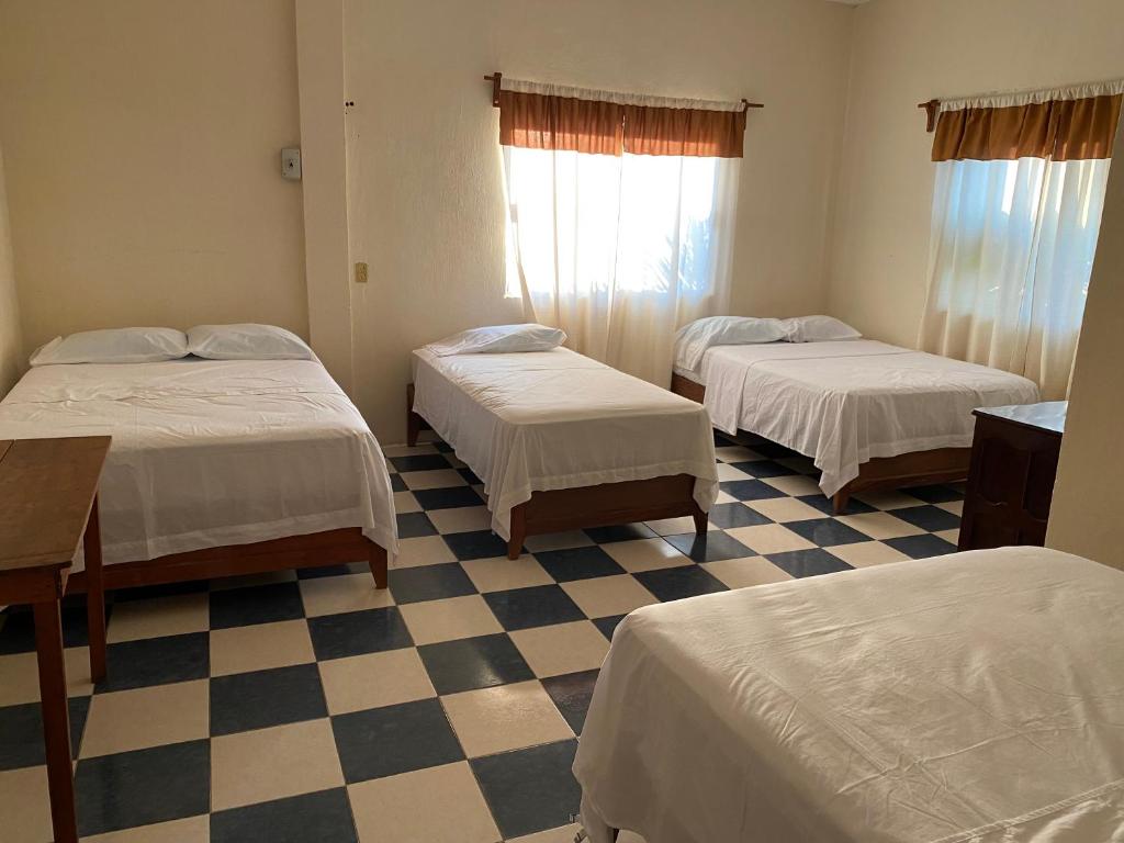 Zimmer mit 3 Betten und einem karierten Boden in der Unterkunft Hotel Villa del Mar in Tonalá