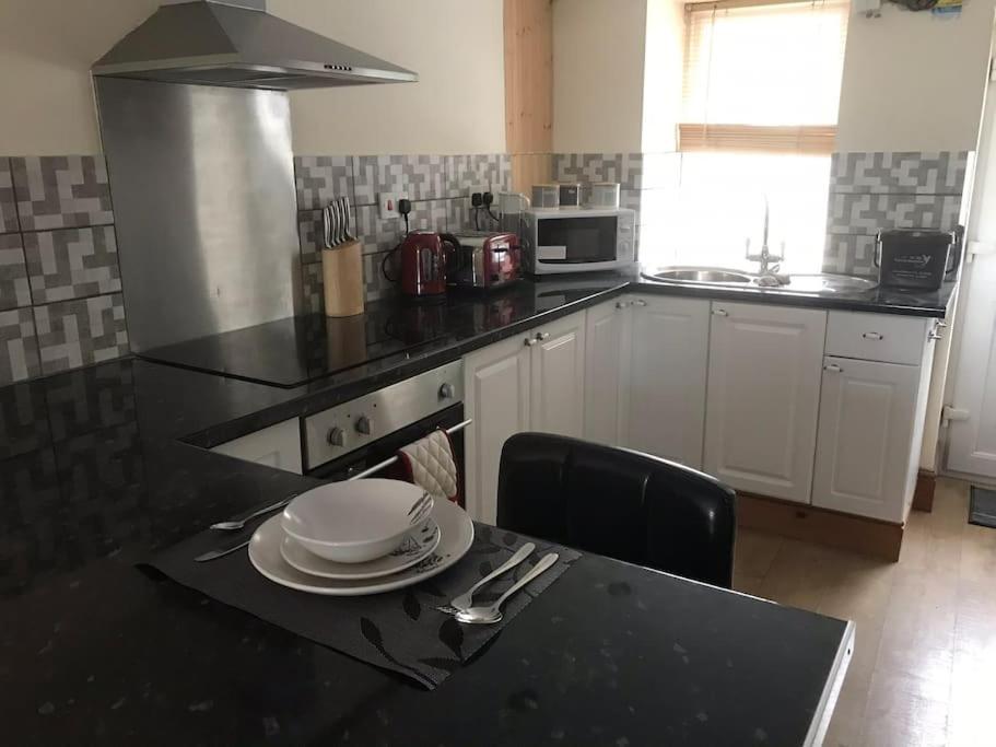 a kitchen with a black counter top and a table at Cosy Cottage in Garnant in Garnant