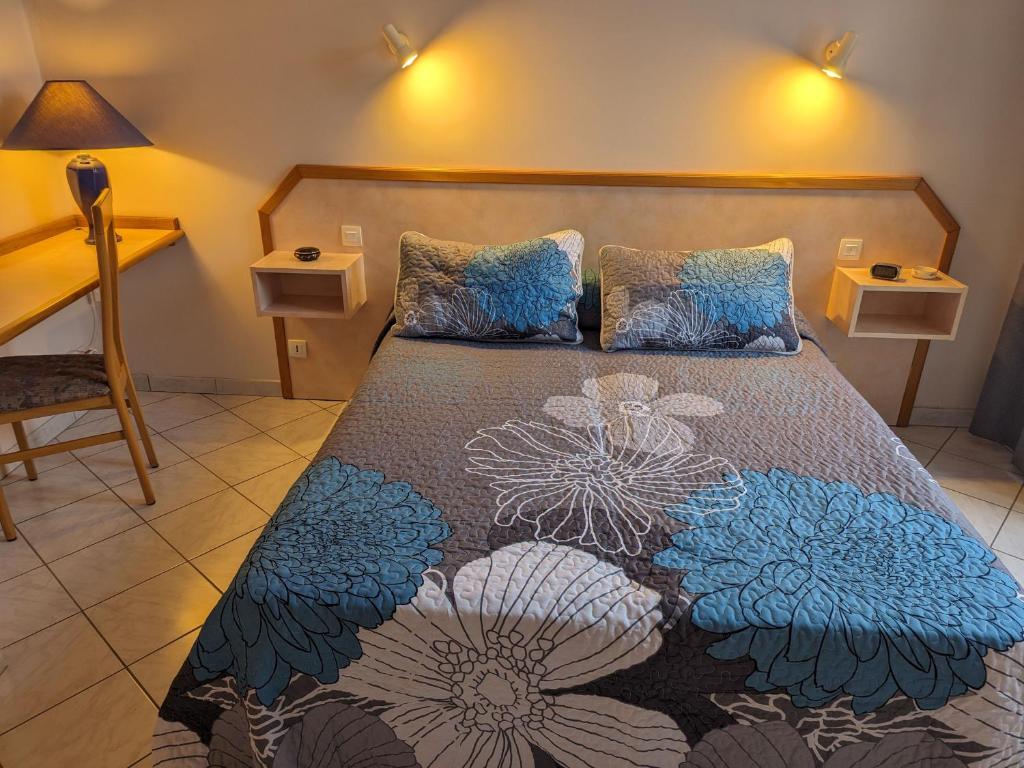 ein Schlafzimmer mit einem Bett mit einer Blumendecke in der Unterkunft Gîte Bourbonne-les-Bains, 2 pièces, 2 personnes - FR-1-611-100 in Bourbonne-les-Bains