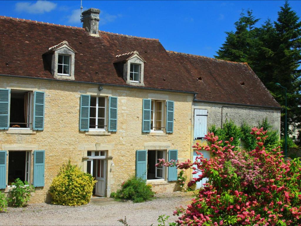 ein altes Backsteinhaus mit blauen Fensterläden und Blumen in der Unterkunft Gîte Ri, 4 pièces, 6 personnes - FR-1-497-193 in Ri