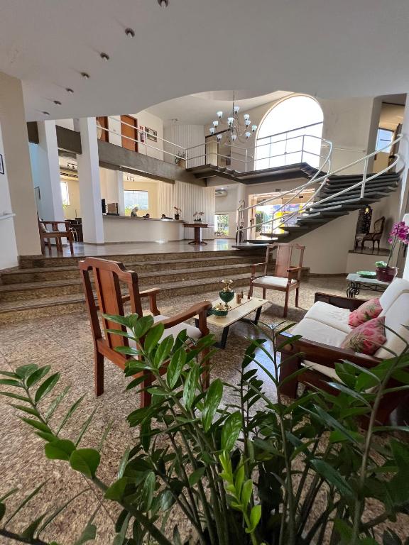 een woonkamer met een bank en stoelen en een trap bij Hotel Guanabara Palace in Andradina