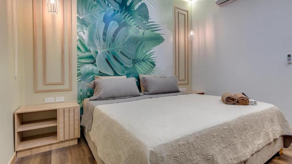 - une chambre avec un grand lit et une fresque murale tropicale dans l'établissement Miami Hotel Cartagena - Luxury Apartments, à Carthagène des Indes