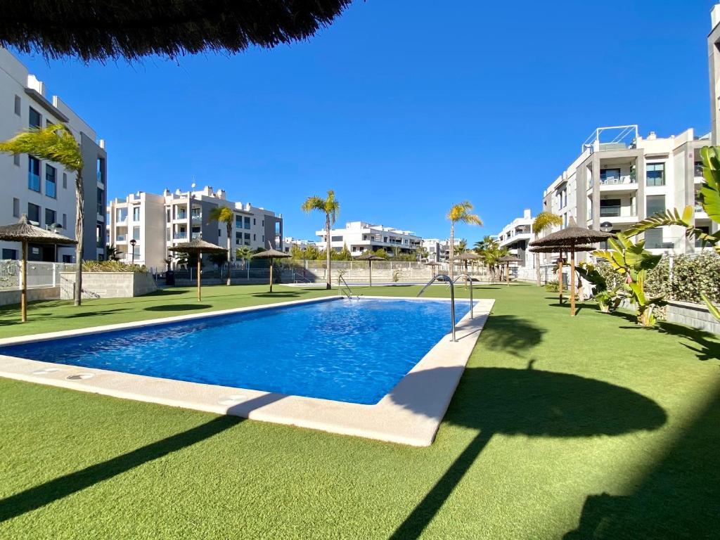 a swimming pool in the middle of a lawn with buildings at Casa Onesta Luxery apartment with private rooftop terrace in Orihuela