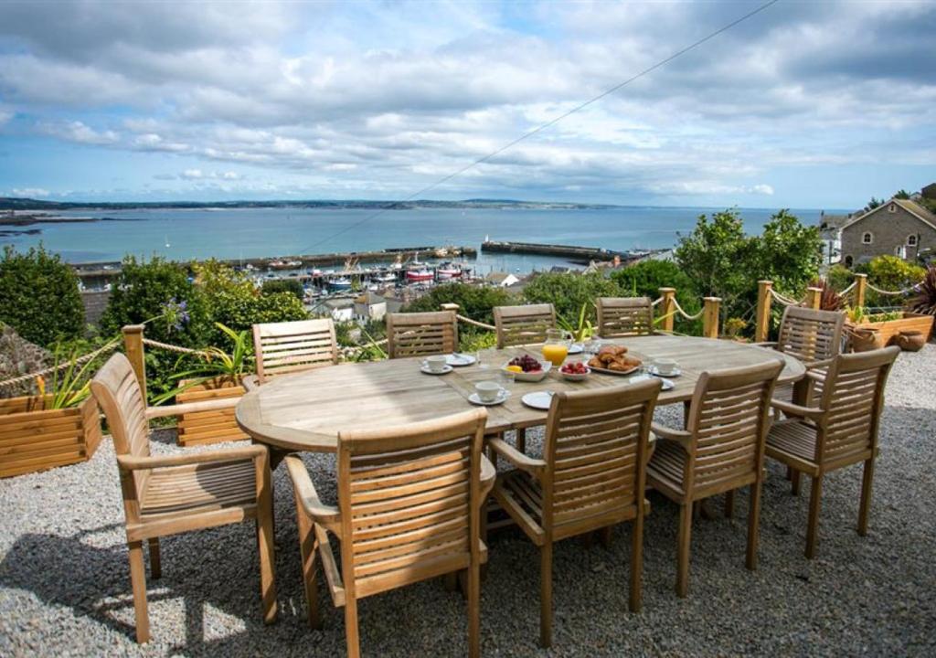 a wooden table and chairs with a view of the ocean at Orchard Cottage in Newlyn