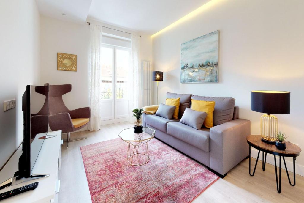 ein Wohnzimmer mit einem Sofa und einem TV in der Unterkunft FUENCARRAL II in Madrid