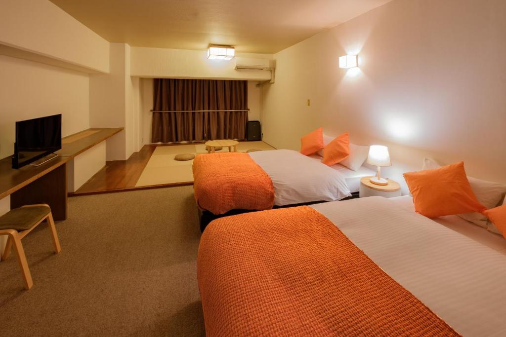 a hotel room with two beds and a flat screen tv at Miyazaki Mango Hotel - Vacation STAY 58306v in Miyazaki