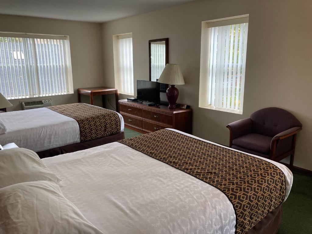 a hotel room with two beds and a chair at The Hotel Pratt in Cooperstown