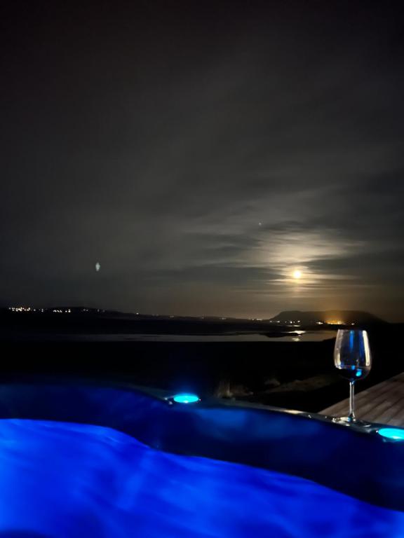 a glass of wine sitting on a table at night at Luxury villa with hot tub & amazing view in Reykholt