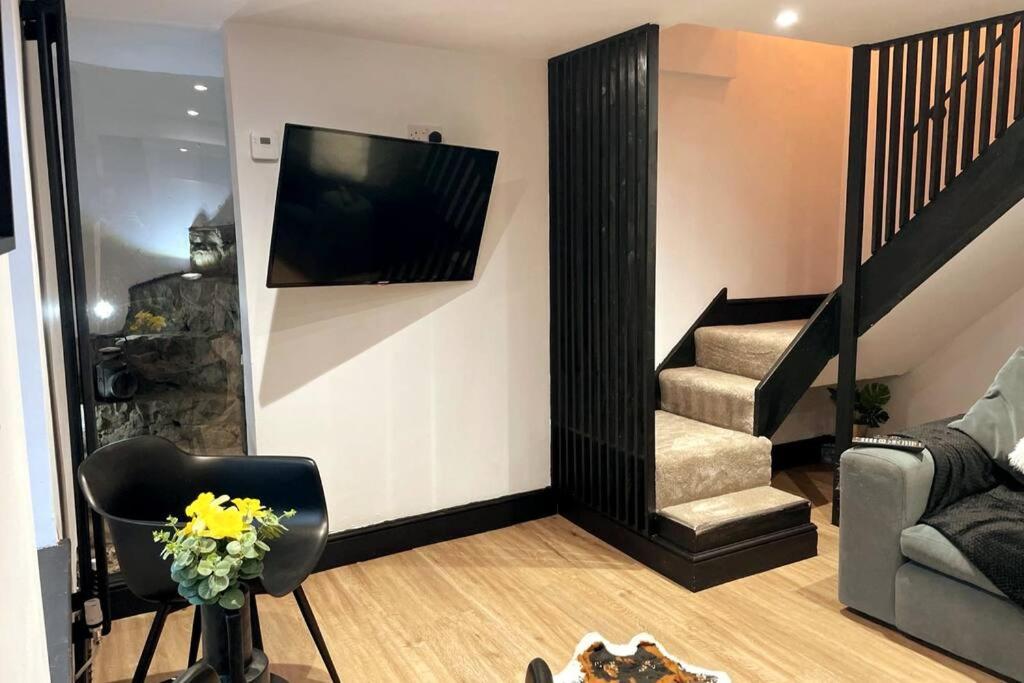 a living room with a television and a stair case at Cosy Cottage By MGroupSA in Aberdare