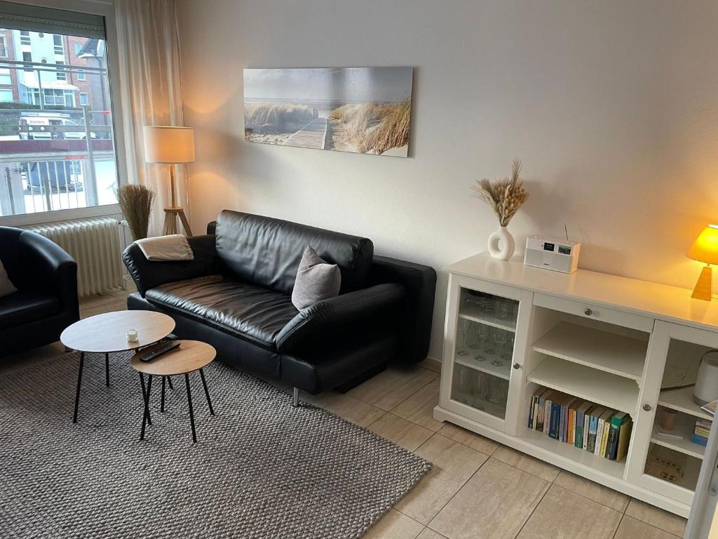 uma sala de estar com um sofá de couro preto e uma mesa em Haus Baltic Koje 04 em Cuxhaven