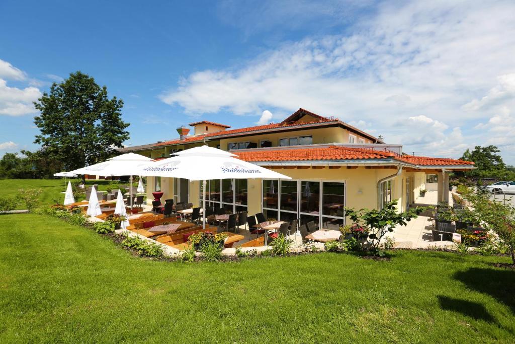 ein Haus mit Stühlen und Sonnenschirmen in einem Hof in der Unterkunft Hotel Friedenseiche in Benediktbeuern