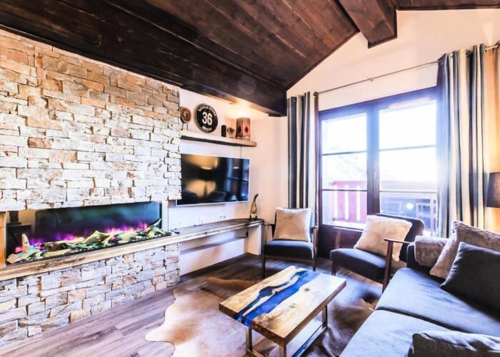a living room with a fireplace and a stone wall at Résidence Les Arcs 1950 Le Village - maeva Home - Appartement 3 pièces 6 personnes vue sur le Mont Blanc - Prestige - super Home MAE-4490 in Bourg-Saint-Maurice