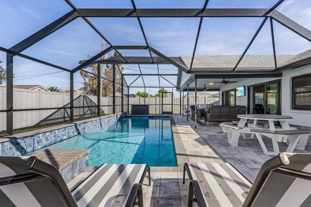 um pátio com uma piscina com cadeiras e mesas em Anchors Away - Pool with Spa - Garage Game Room em Cape Coral