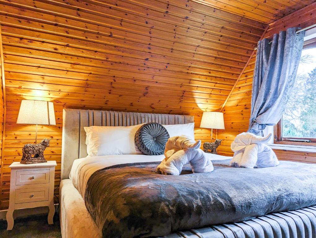dois animais de peluche estão sentados numa cama num quarto em Macha 3 - Hot Tub-Perth-Pets-Family-Luxury-Cabin em Perth