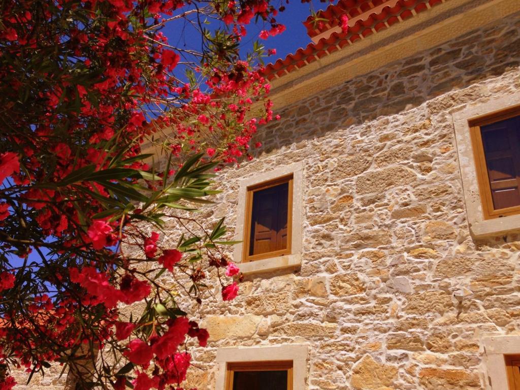 un edificio de piedra con ventanas y un árbol con flores rojas en Otium Country House, en Alvorge