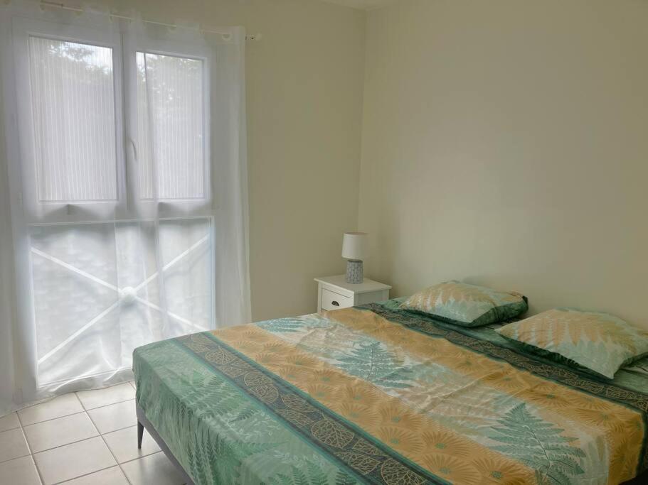 a white bedroom with a bed and a window at Orchidée, Spacieux & Vue mer in Les Trois-Îlets