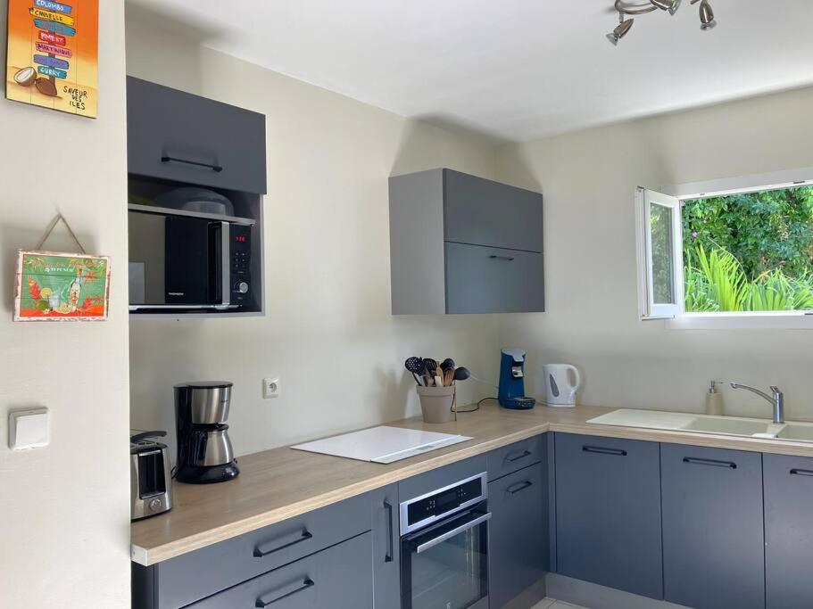 a kitchen with blue cabinets and a sink and a window at Orchidée, Spacieux & Vue mer in Les Trois-Îlets