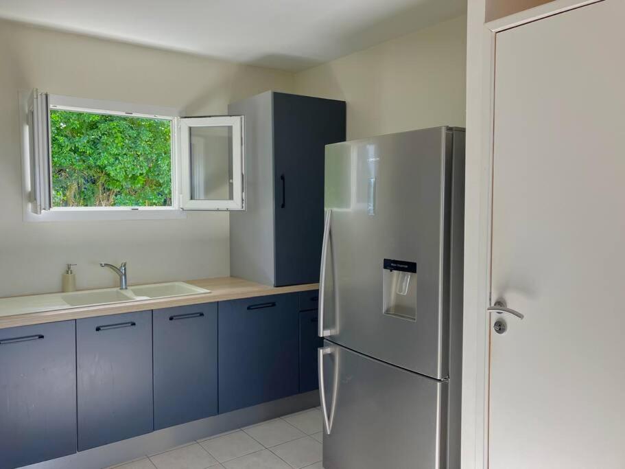 a kitchen with blue cabinets and a stainless steel refrigerator at Orchidée, Spacieux & Vue mer in Les Trois-Îlets