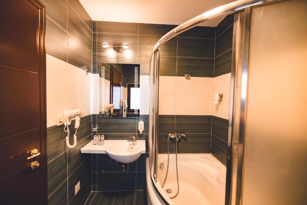 a bathroom with a shower and a sink and a tub at Etno selo Stanišići Hotel Leonida in Dijelovi