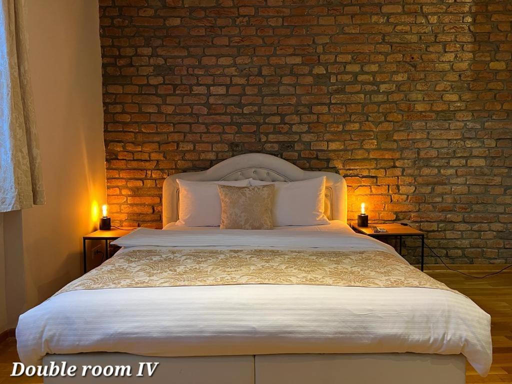 a bedroom with a large bed with a brick wall at Metropolitan Rooms in Belgrade