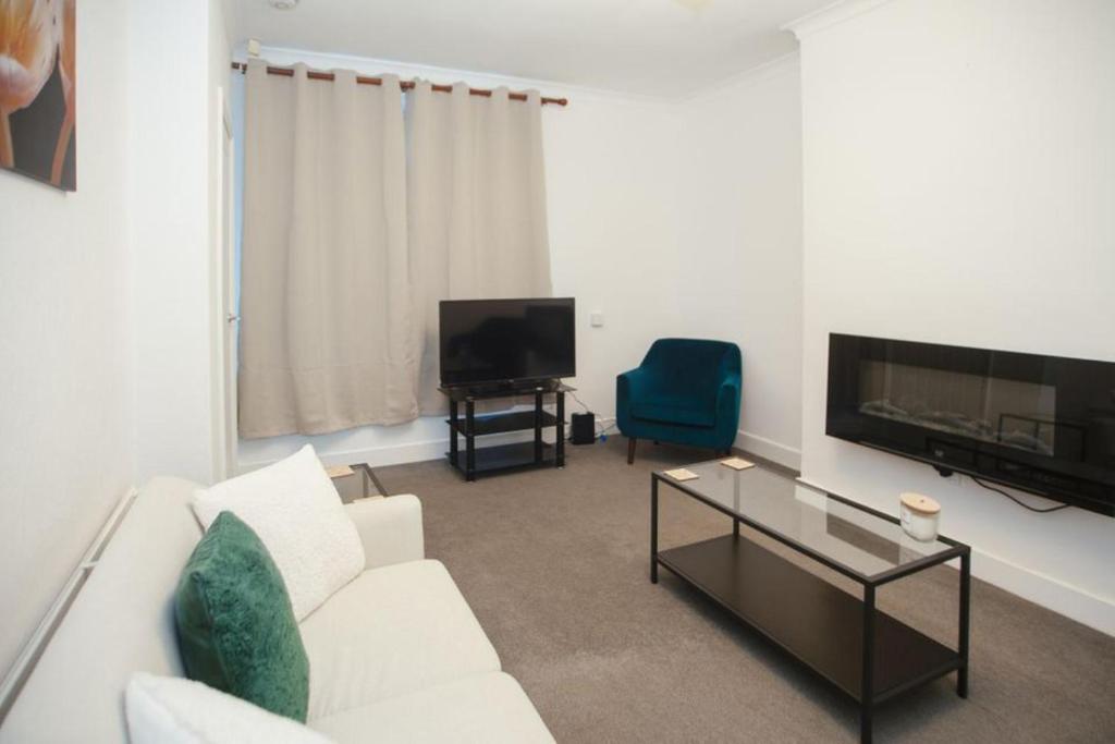 ein Wohnzimmer mit einem weißen Sofa und einem TV in der Unterkunft Lovely 2 Bedroom House Sheffield Central Location in Sheffield