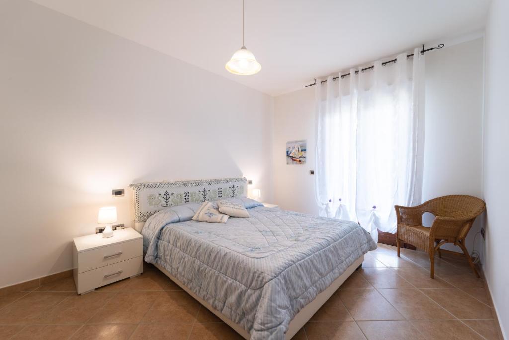 a white bedroom with a bed and a chair at Casa delle vele in Alghero