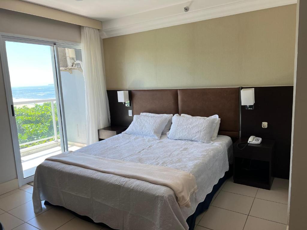 sypialnia z dużym łóżkiem i dużym oknem w obiekcie Flat com Vista Deslumbrante na Praia do Pecado w mieście Macaé